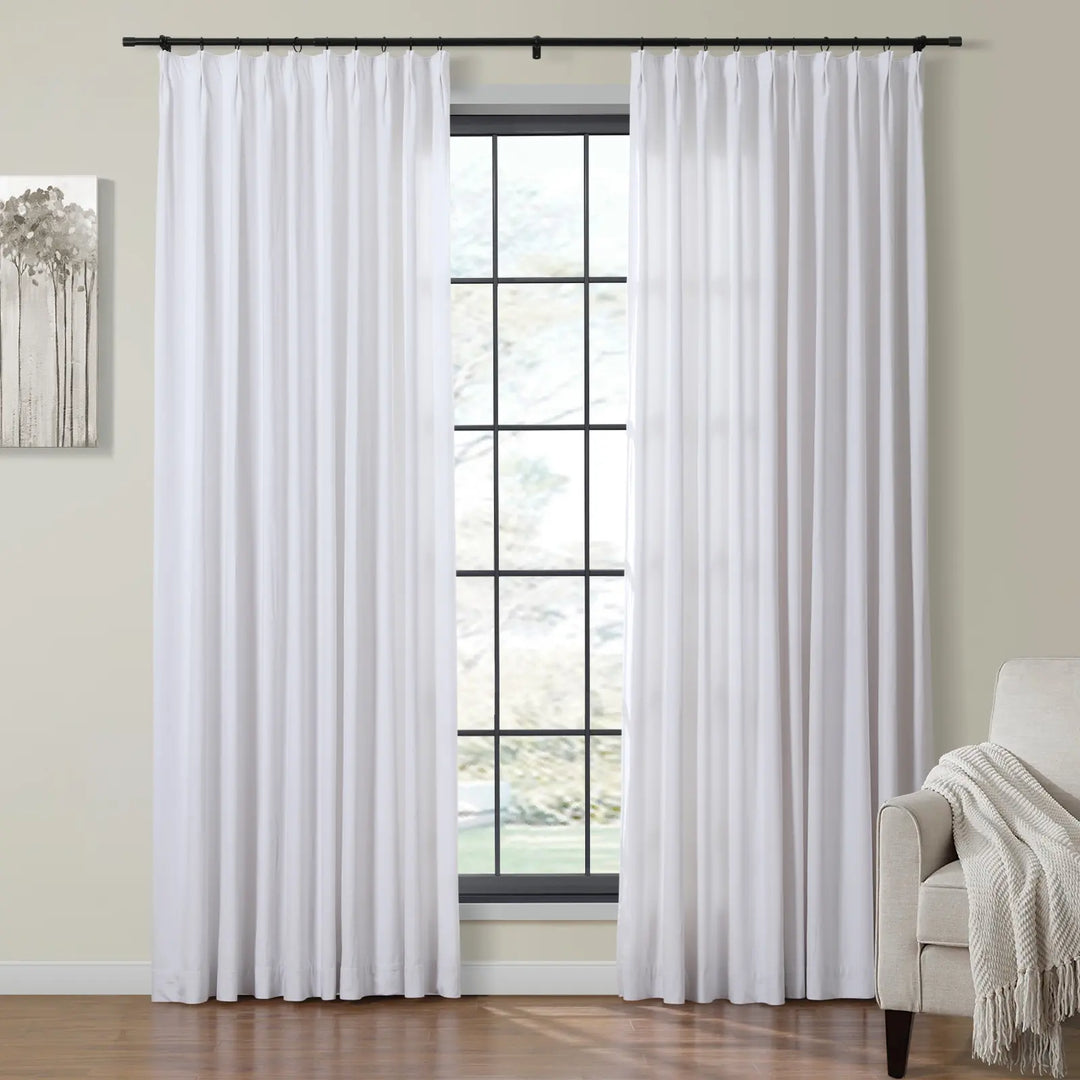 Bright white sheer curtains beside a large window in a cozy living room.