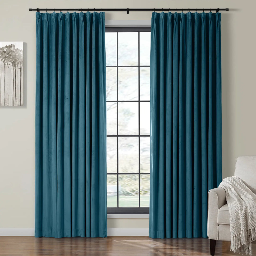 Teal velvet curtains draping beside a large window in a cozy living room.