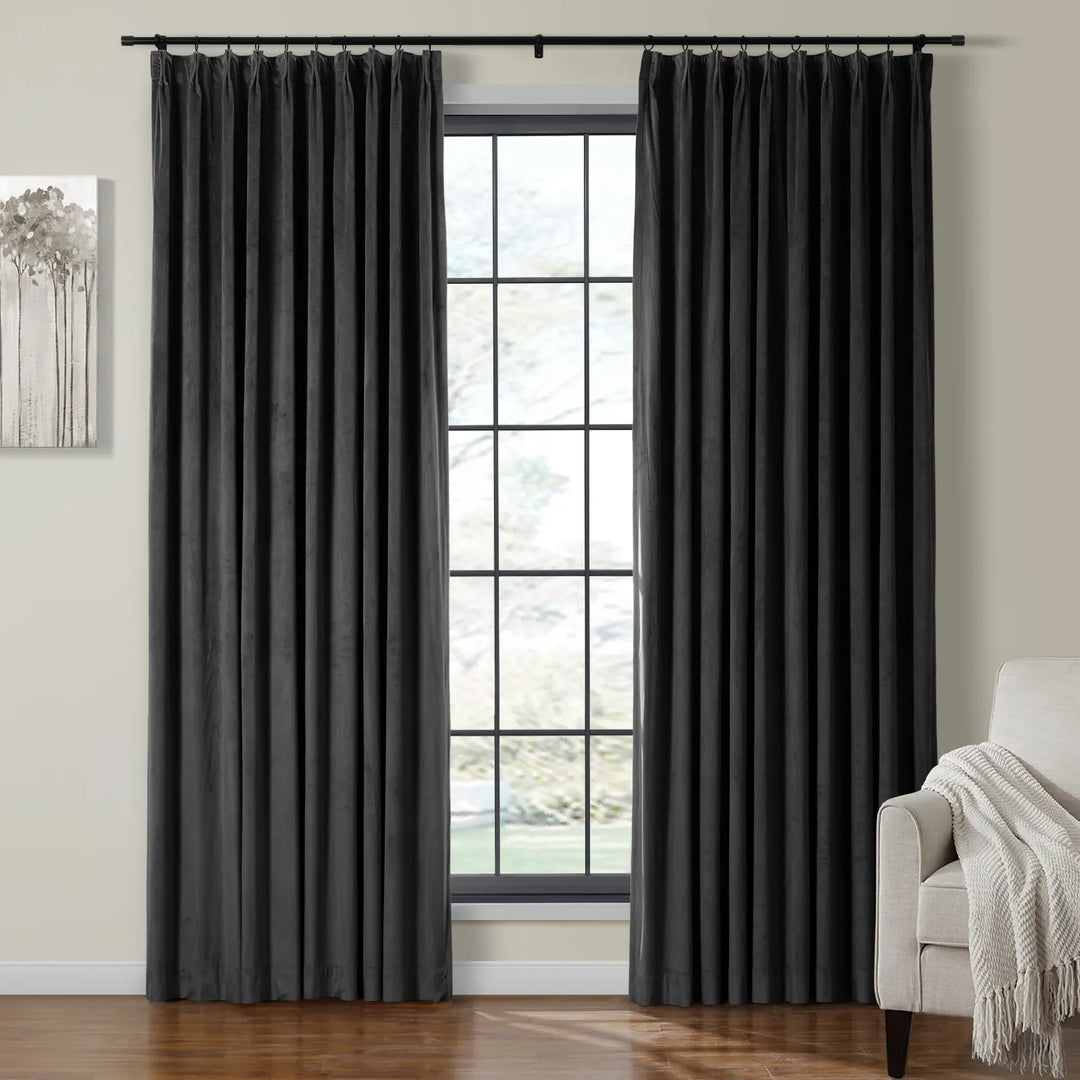 Dark grey velvet curtains on black rod framing window in cozy living room.