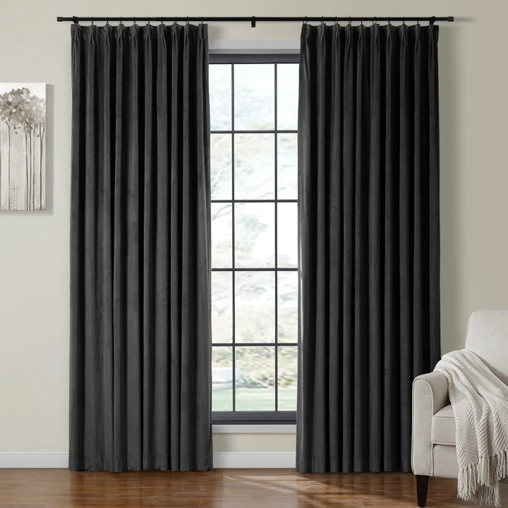 Dark grey velvet curtains on black rod framing window in cozy living room.