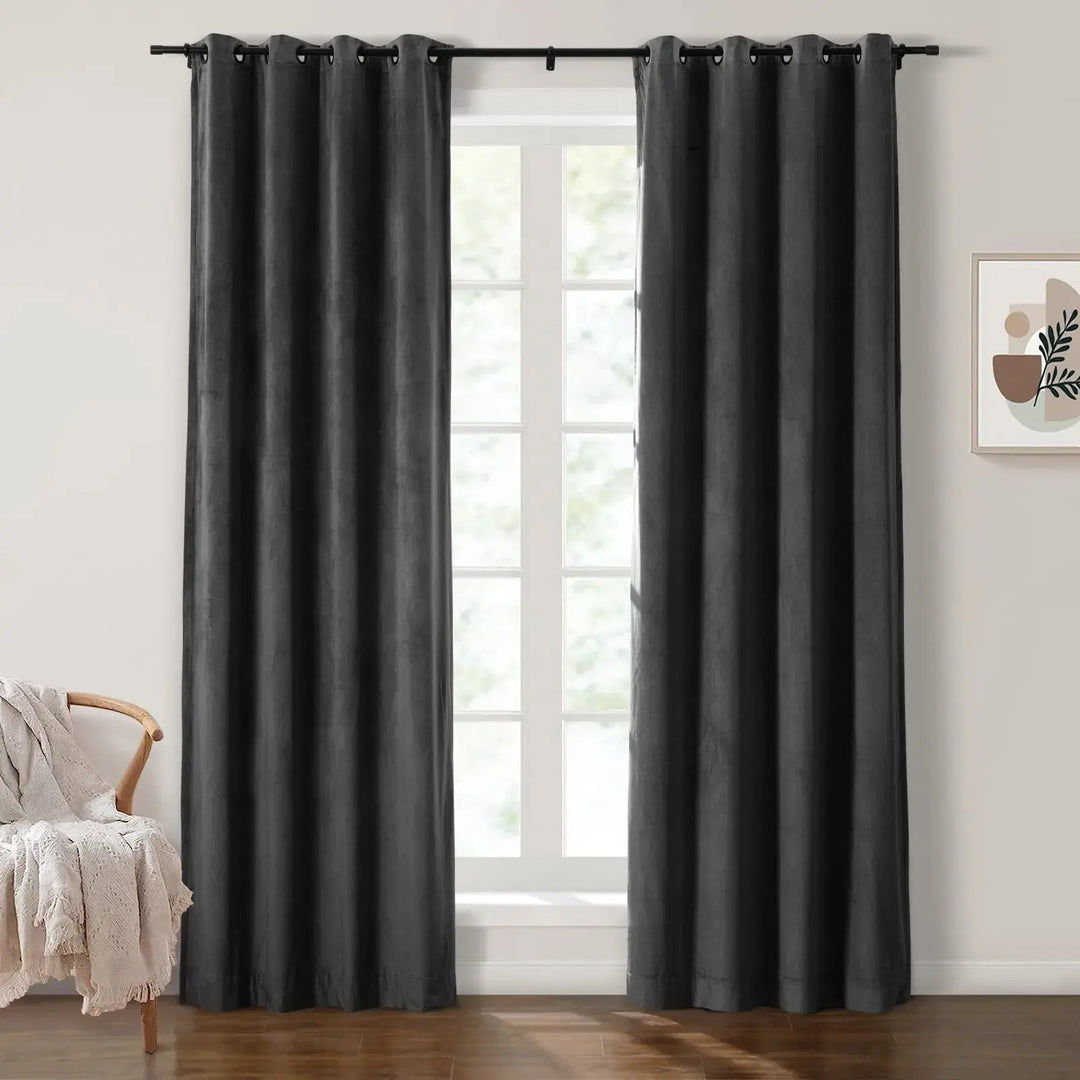 Dark gray velvet grommet curtains framing large windows in a bright room.