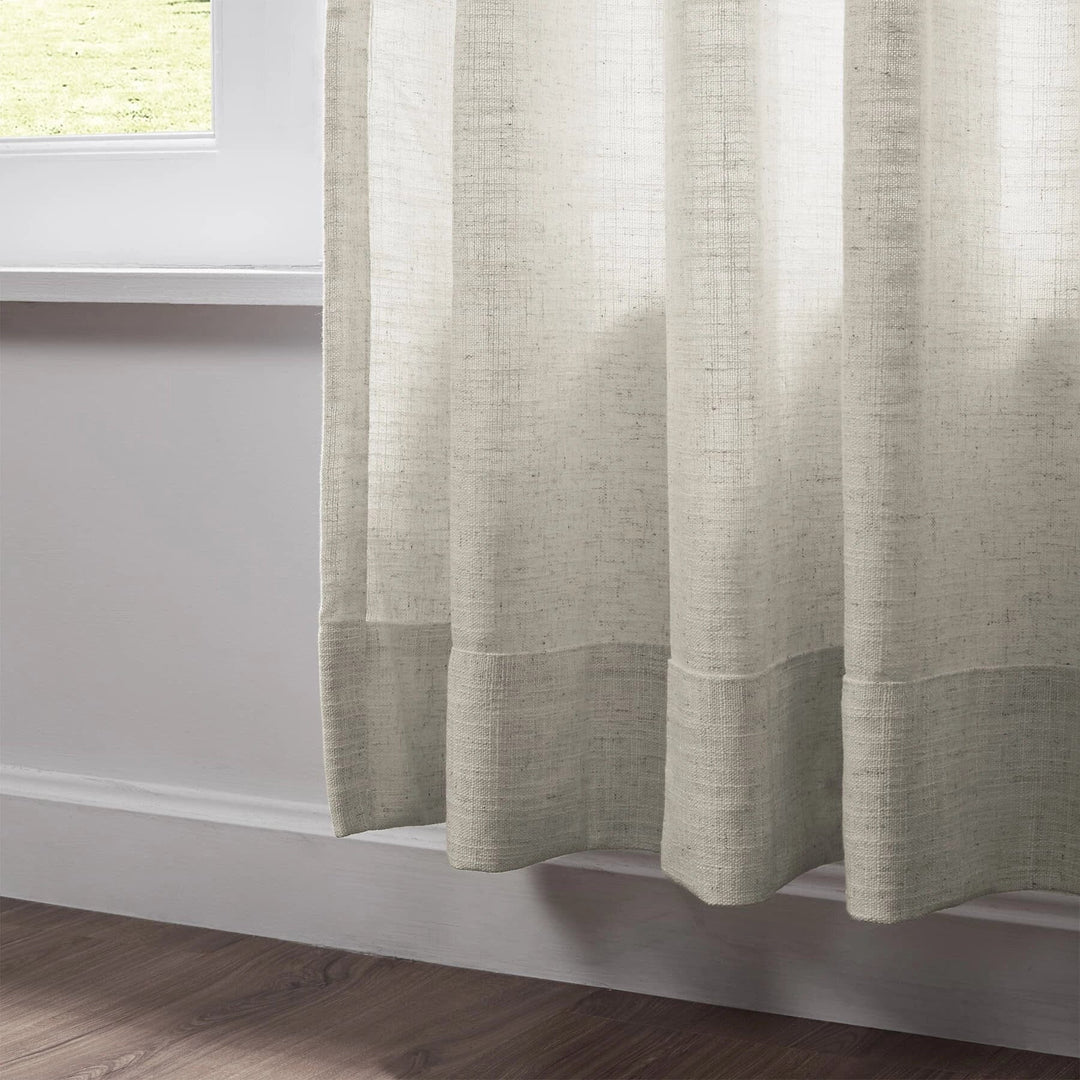 Close-up of pleated beige linen curtains showcasing texture and elegant draping