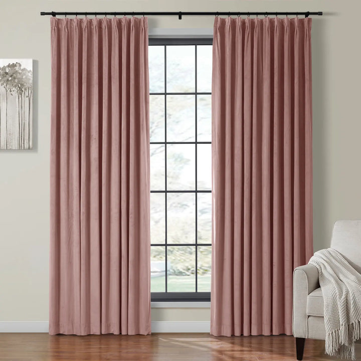 Pleated pink velvet curtains hanging beside a large window in a cozy living room.