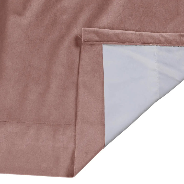 Close-up of blush velvet curtain hem with smooth texture and contrasting inner lining.