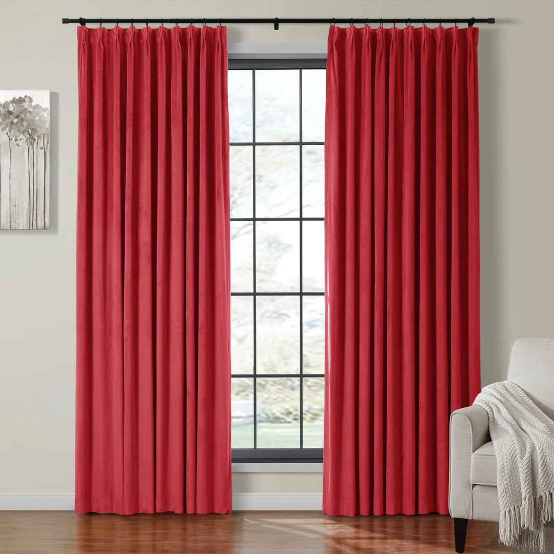 Red velvet curtains on black rod framing a large window in a cozy living room.