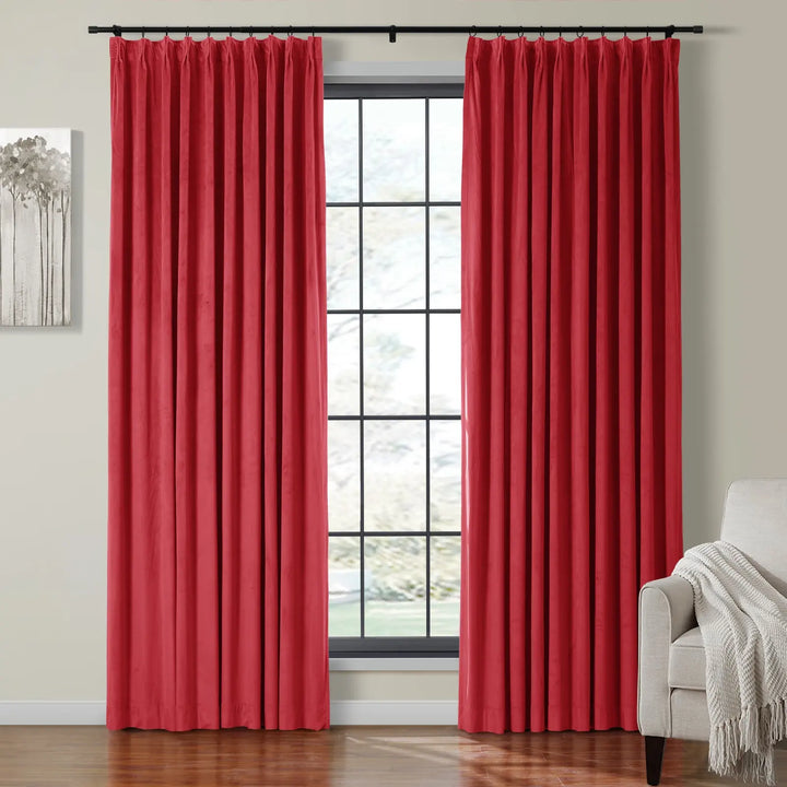 Red velvet curtains on black rod framing a large window in a cozy living room.
