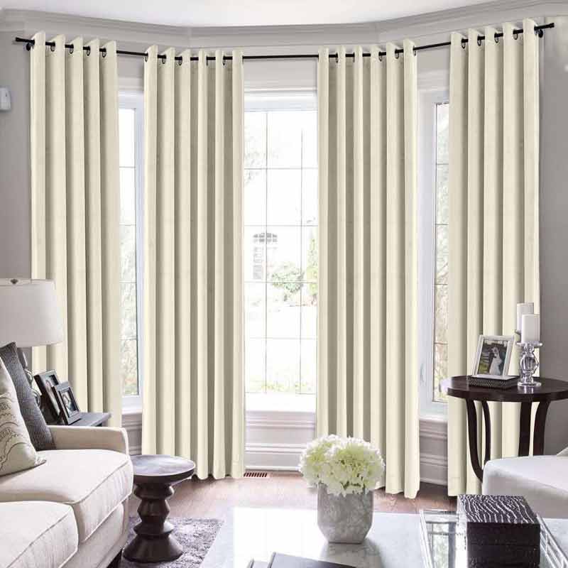 Beige grommet curtains in a bright living room with large windows and stylish white furniture.