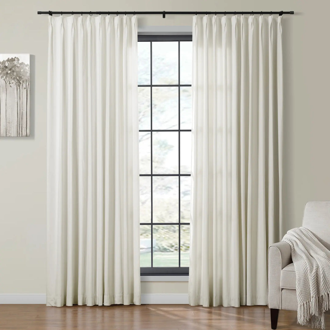 Light cream velvet curtains draping beside a large window in a cozy living room.