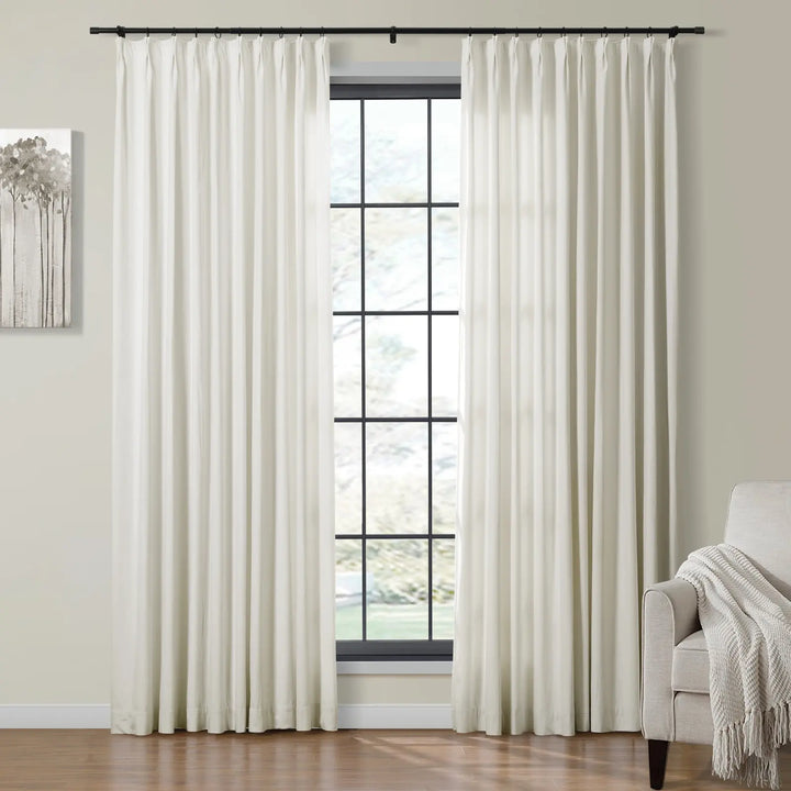 Light cream velvet curtains draping beside a large window in a cozy living room.