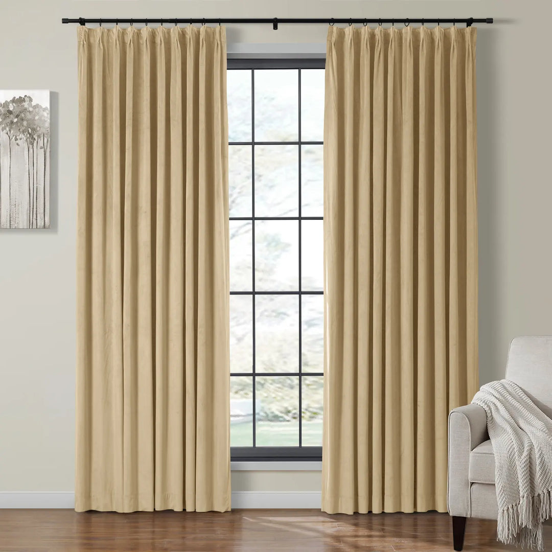 Cream velvet curtains draped beside a large bright window in a cozy living room.