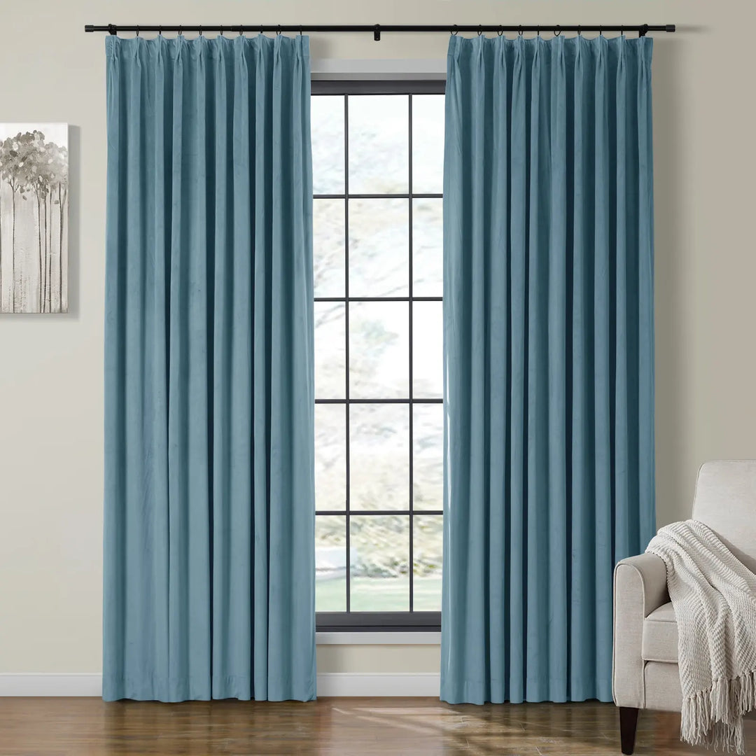 Light blue velvet pleated curtains next to a large window in a cozy living room.