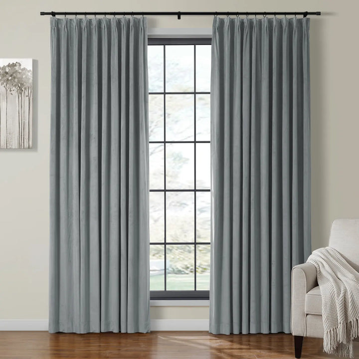 Light grey velvet curtains draping beside a large window in a cozy living room.