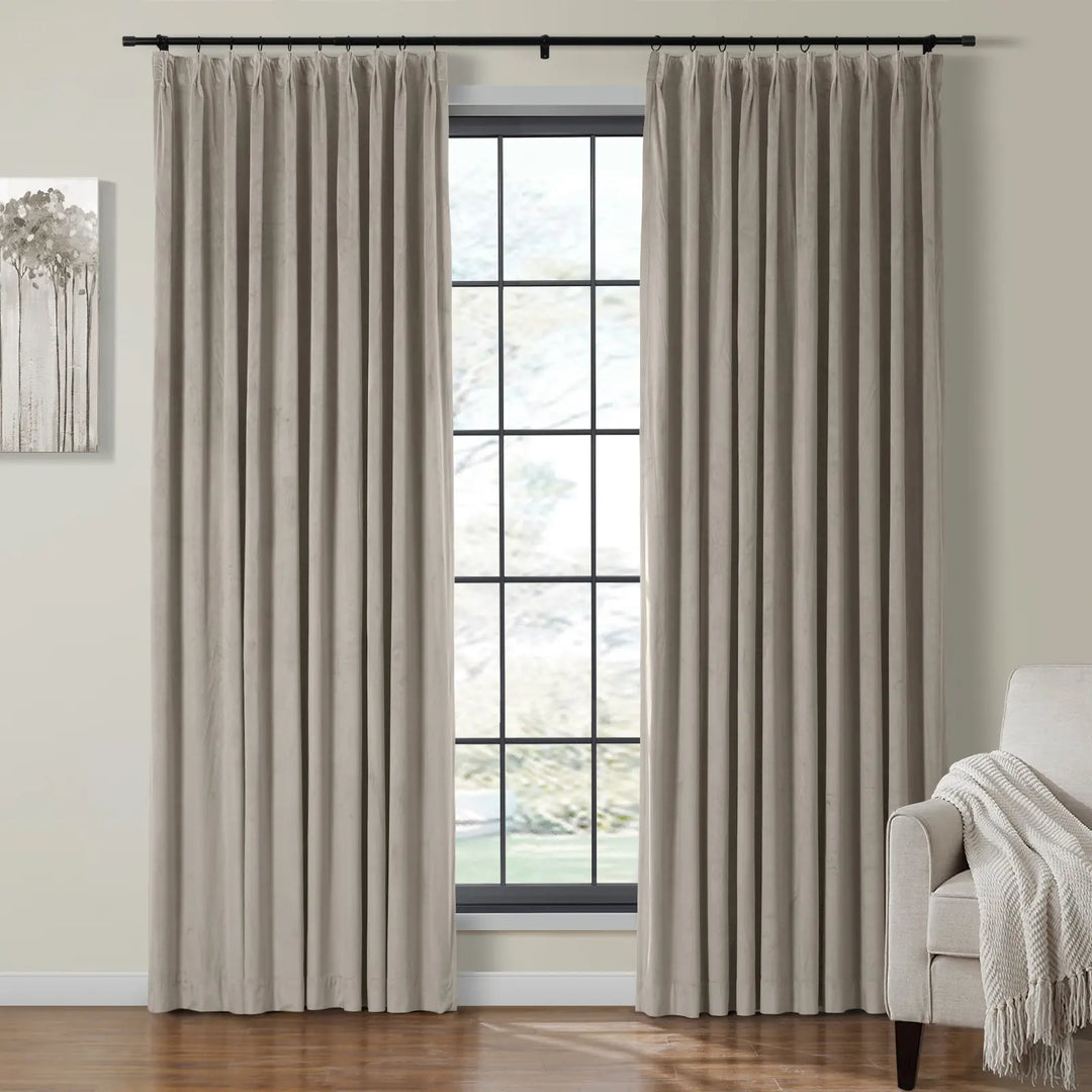 Cream velvet curtains pleated beside a bright window in a cozy living room.