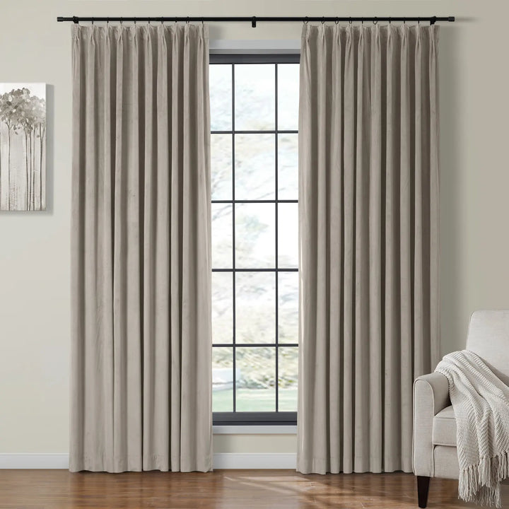 Cream velvet curtains pleated beside a bright window in a cozy living room.