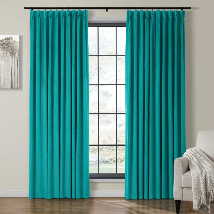 Turquoise pleated velvet curtains on black rod beside bright living room window.