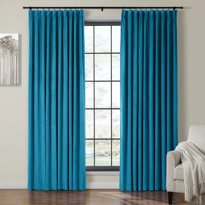 Teal velvet curtains on black rod beside large window in cozy living room.