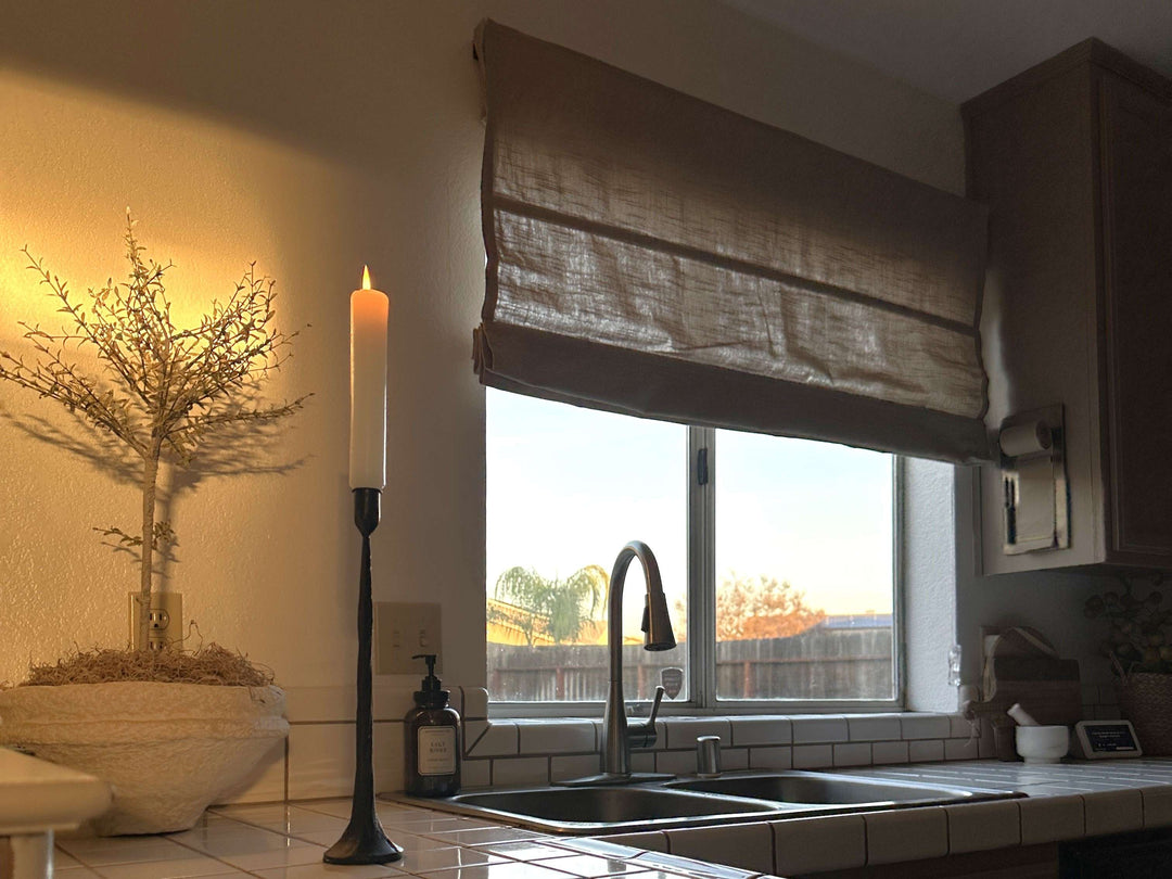 Kitchen scene with a brown, textured Roman shade partially lowered over a double sink